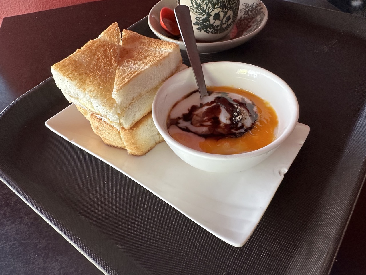 A classic Singaporean breakfast: kaya butter toast, a half cooked egg with soy sauce and pepper